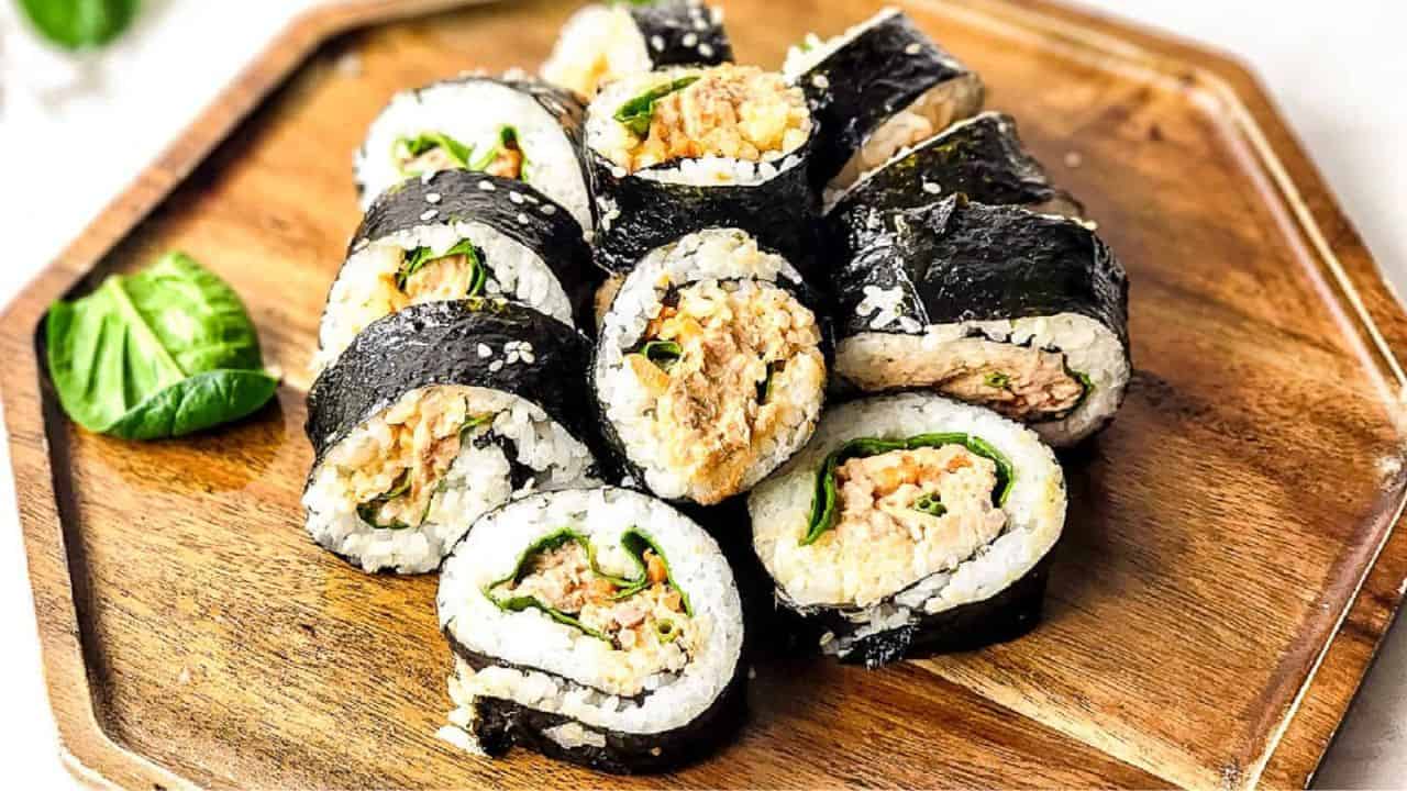 Spicy tuna kimbap on a wood cutting board.