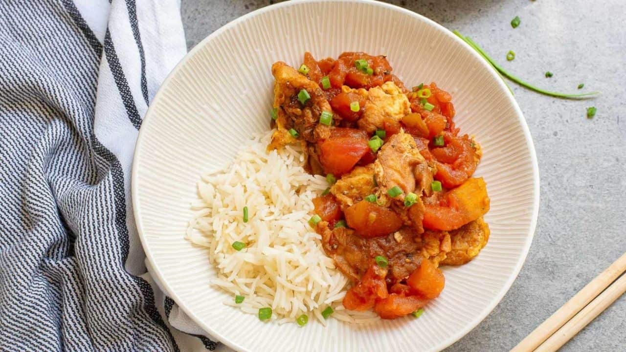 Stir fried tomatoes and eggs in a skillet with chopticks.