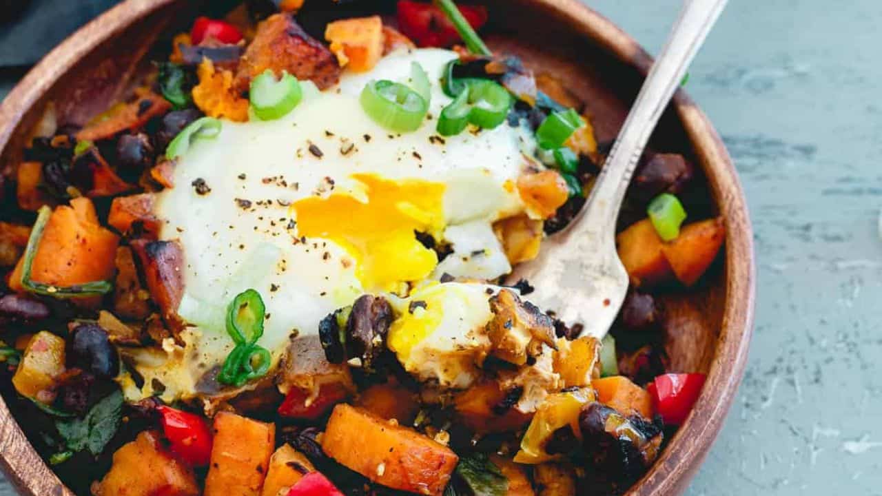 Sweet potato hash with poached eggs in a cast iron skillet.