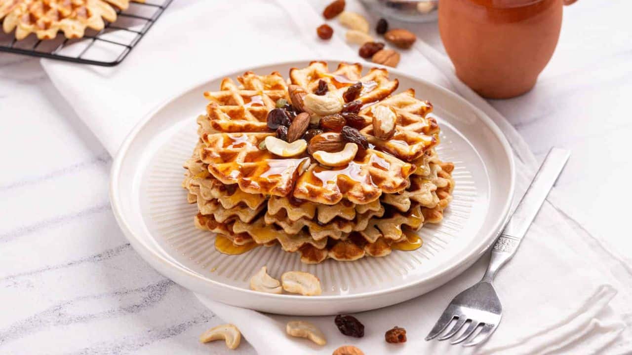An image of a stack of sweet potato waffles with cashews and dried fruits on top.