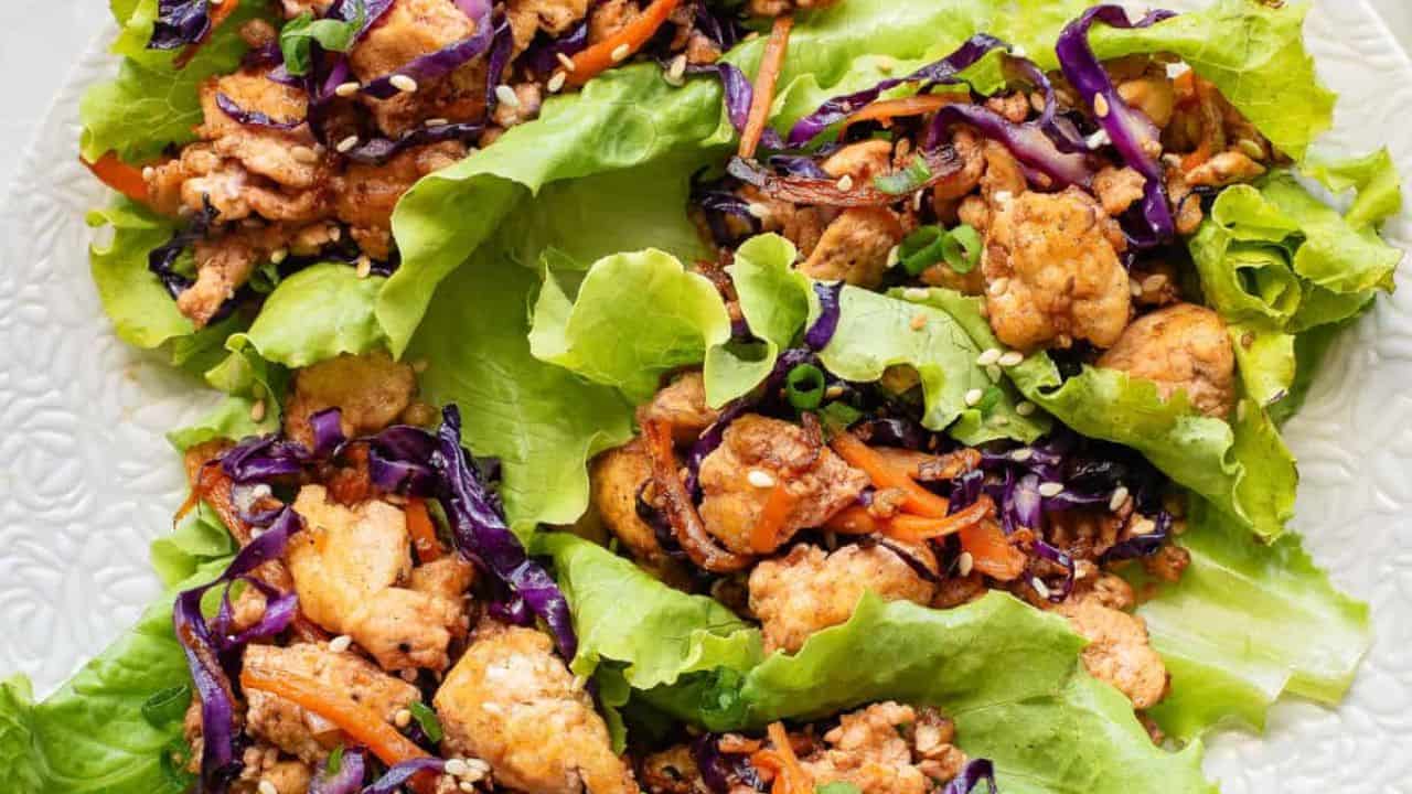 An overview of five tofu lettuce wraps on a white plate.