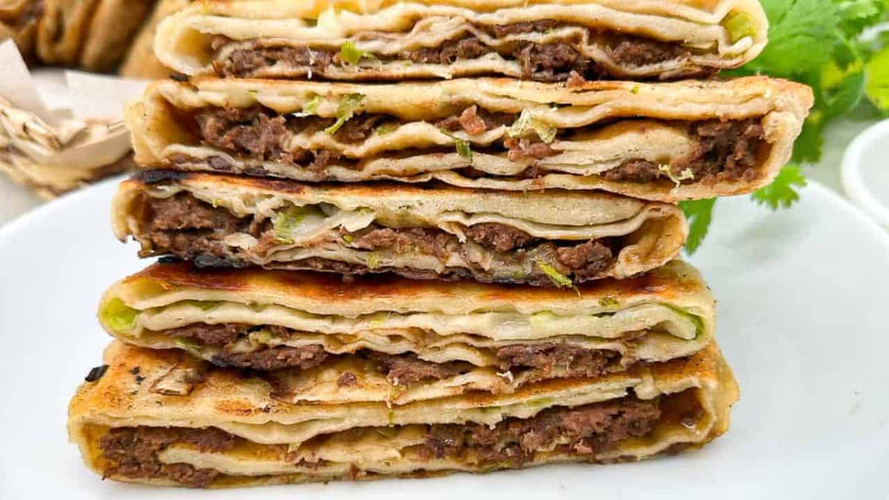 Crispy Chinese meat pies stuffed with seasoned beef filling on a white plate.