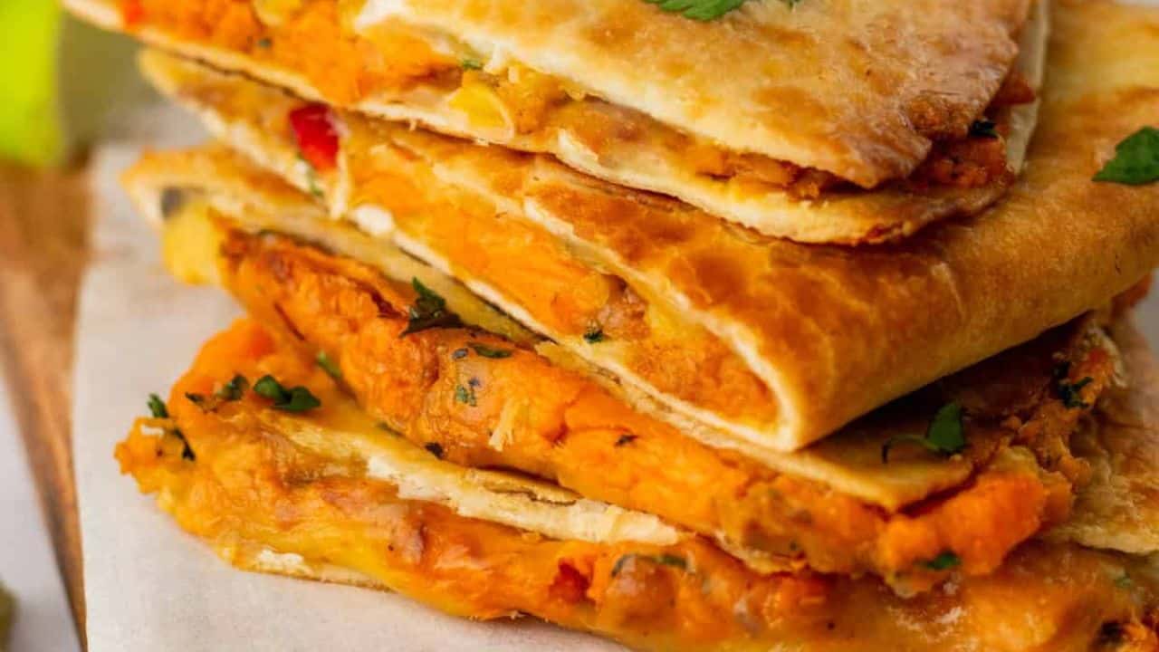 An overhead image of veggie quesadilla on a serving board with a dip on the side.