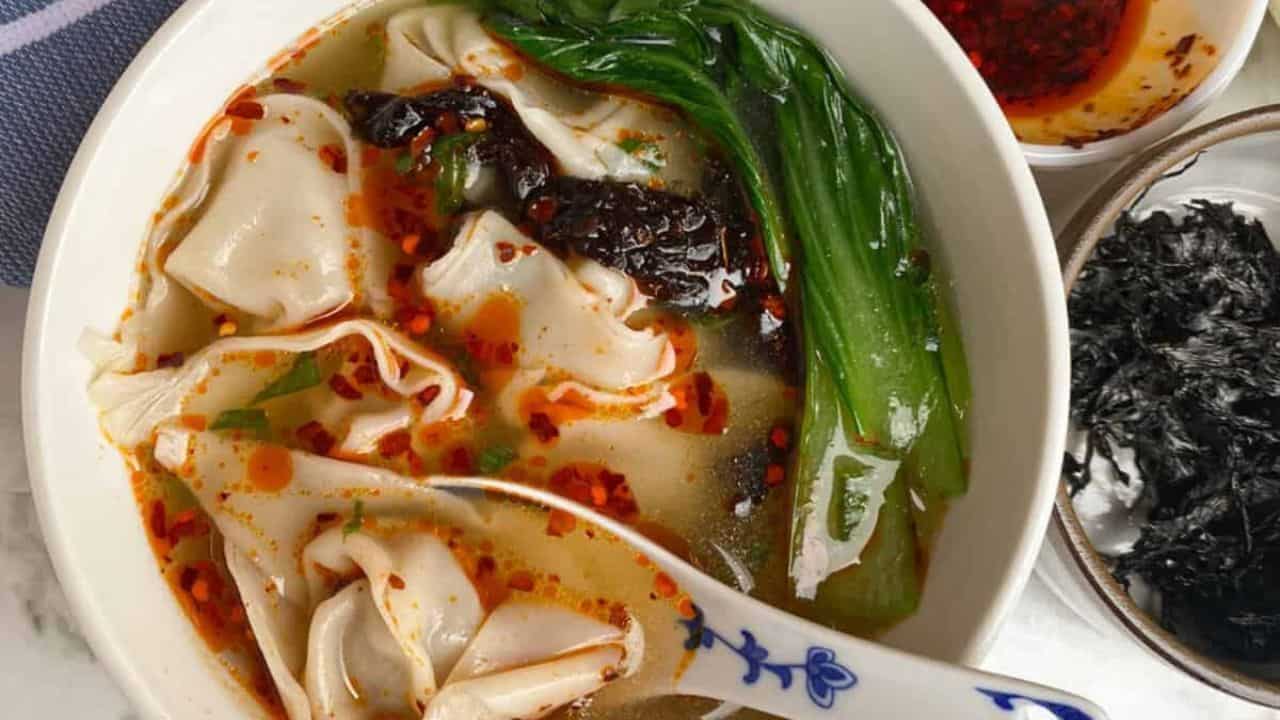 Warm and comforting soup with delicate wontons in a clear, savory broth in a white bowl.