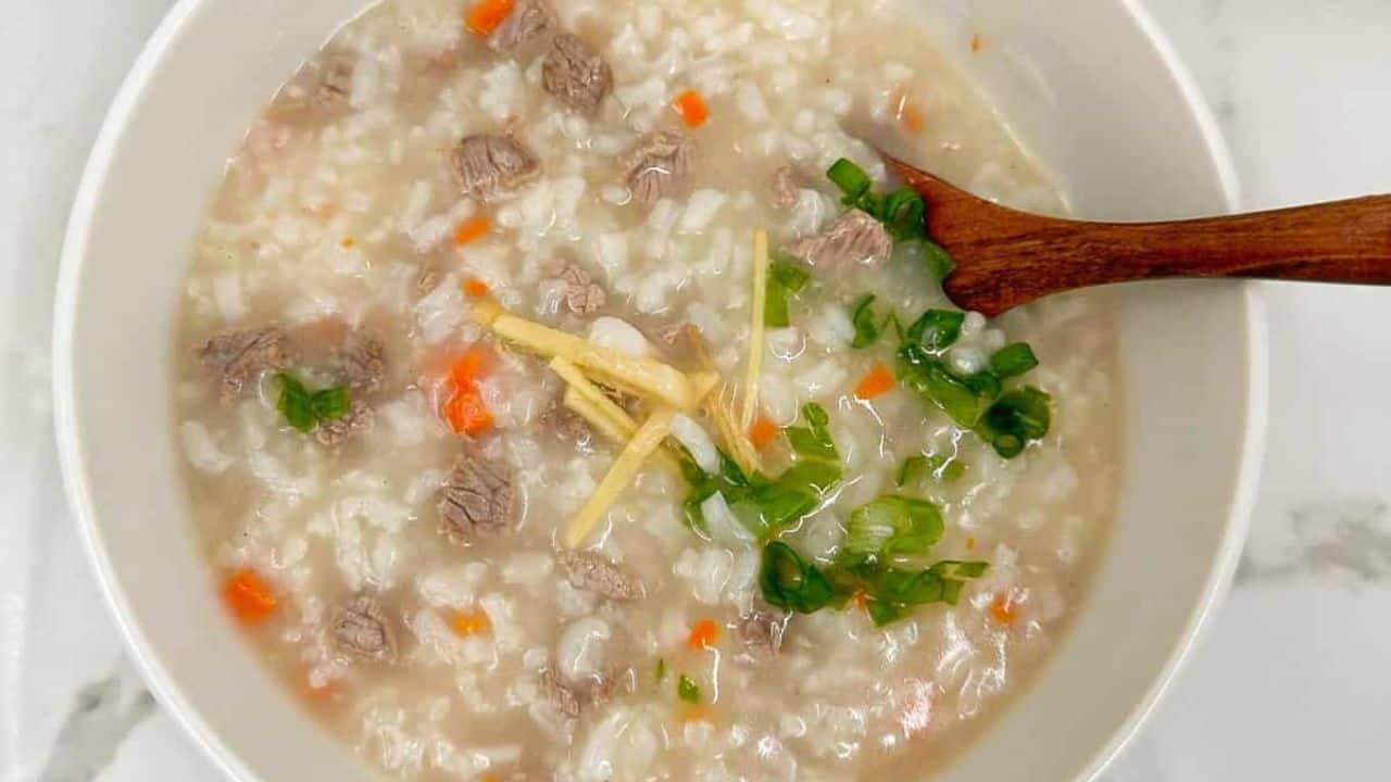 Two bowls of comforting and savory beef congee rice porridge with a wooden spoon.