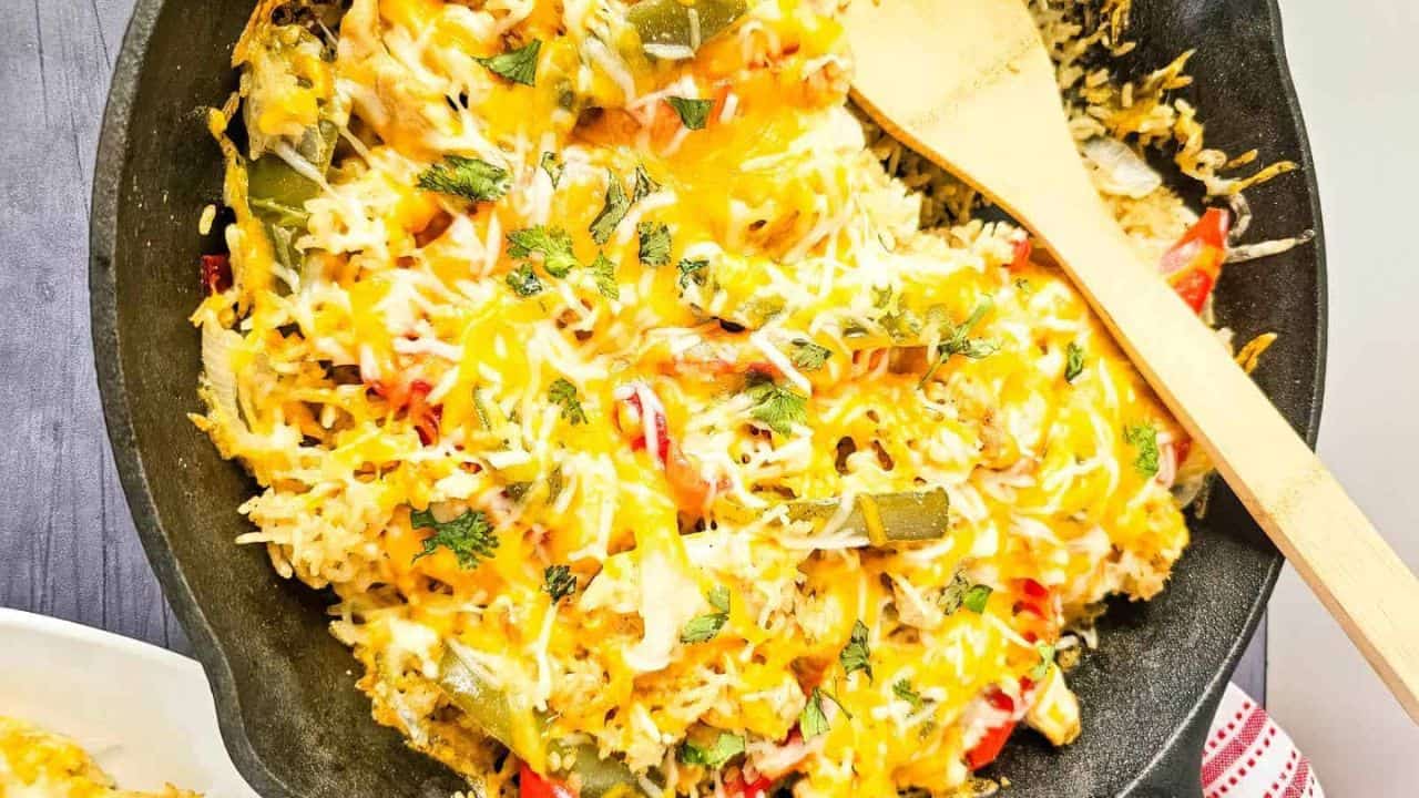 A white plate with cheesy chicken fajita casserole with rice.