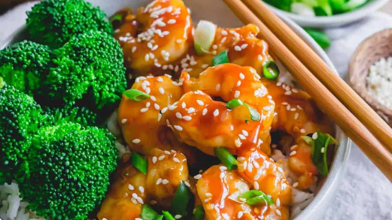 Homemade general tso shrimp with broccoli and rice in a bowl with chopsticks.