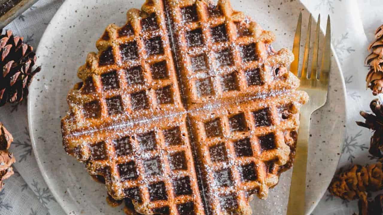 A plate of gingerbread waffles with syrup on it.