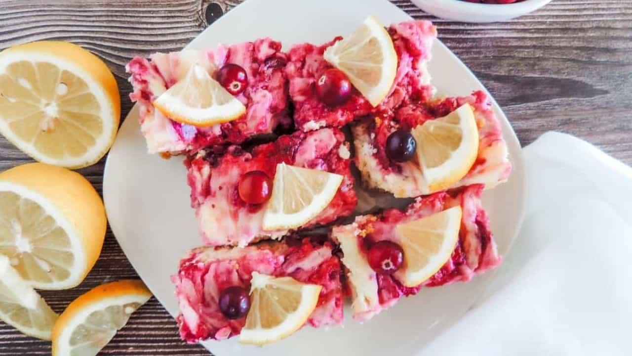 Lemon cranberry cheesecake bars on a white plate.