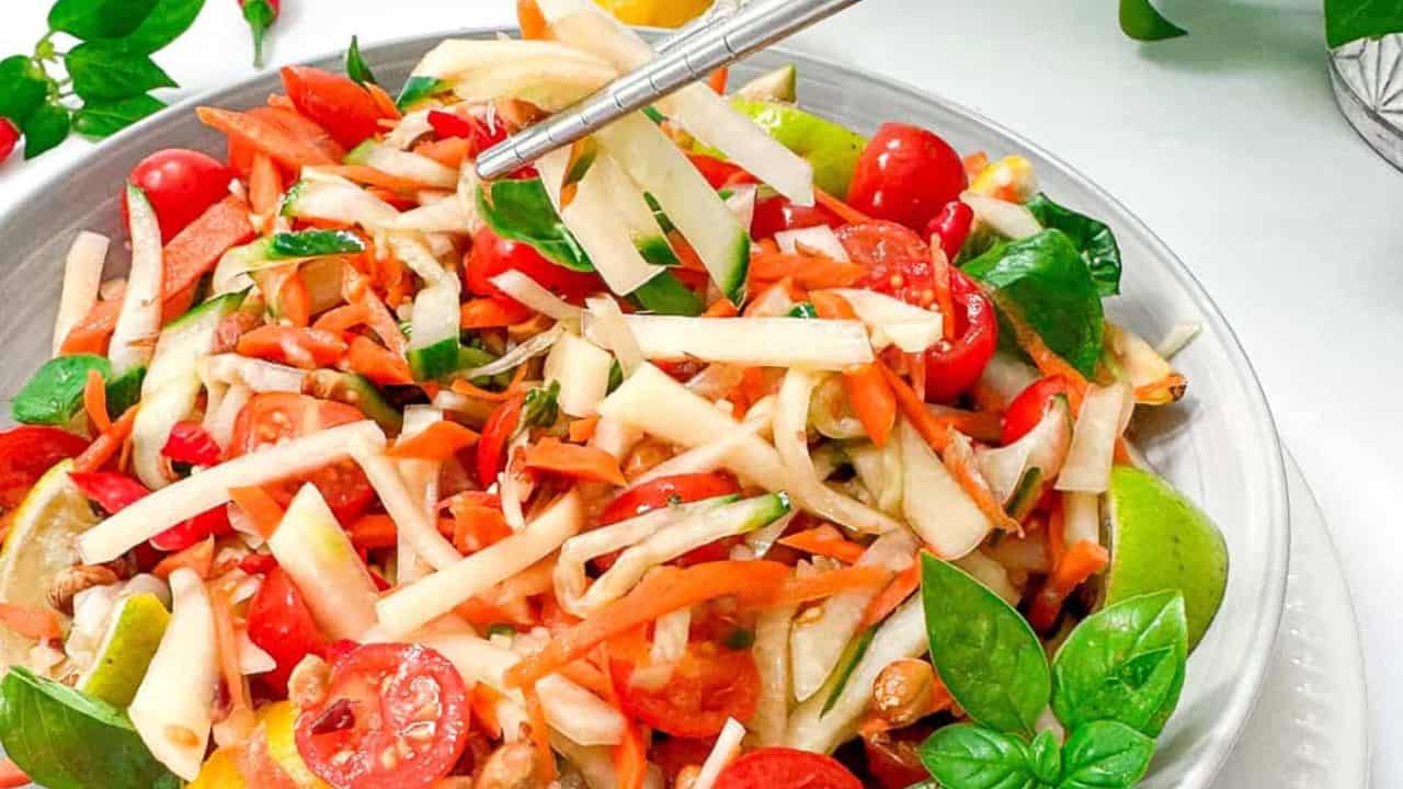 A colorful plate of fresh vietnamese salad featuring vibrant carrots, juicy tomatoes, and green papaya.