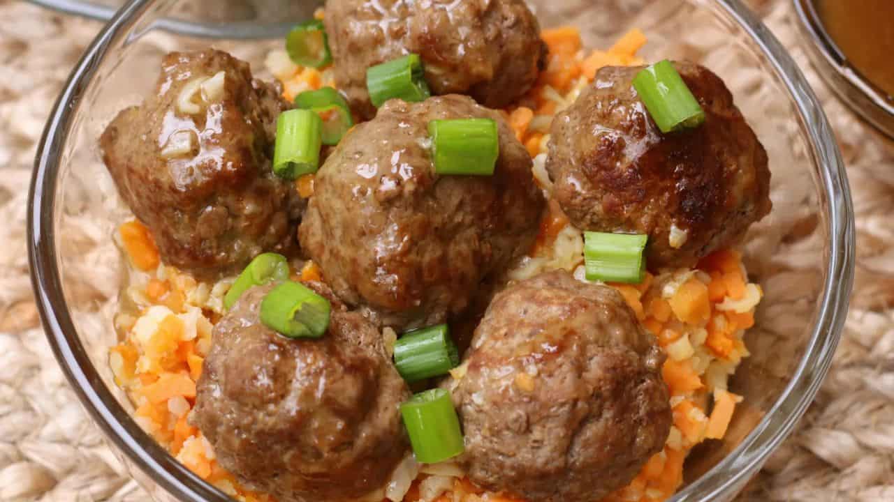 Clear bowl of riced veggies and meatballs.