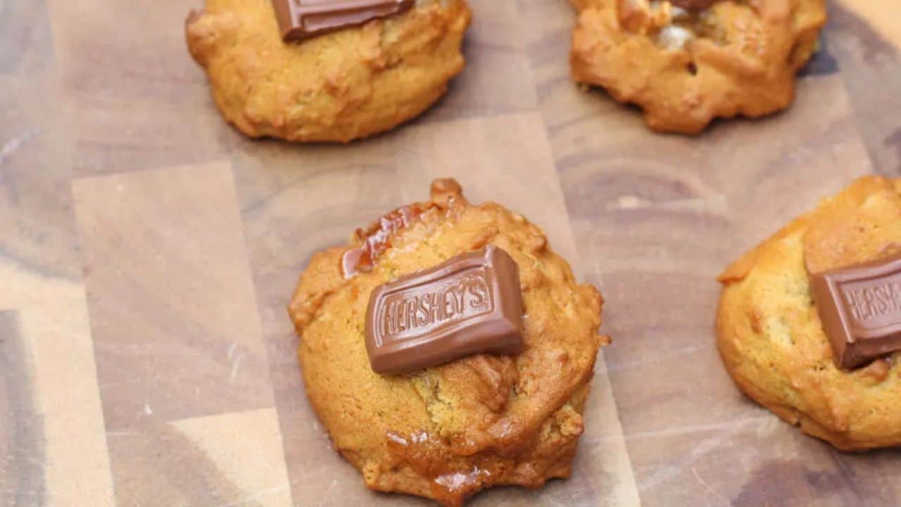Wooden cutting board with cookies on top.