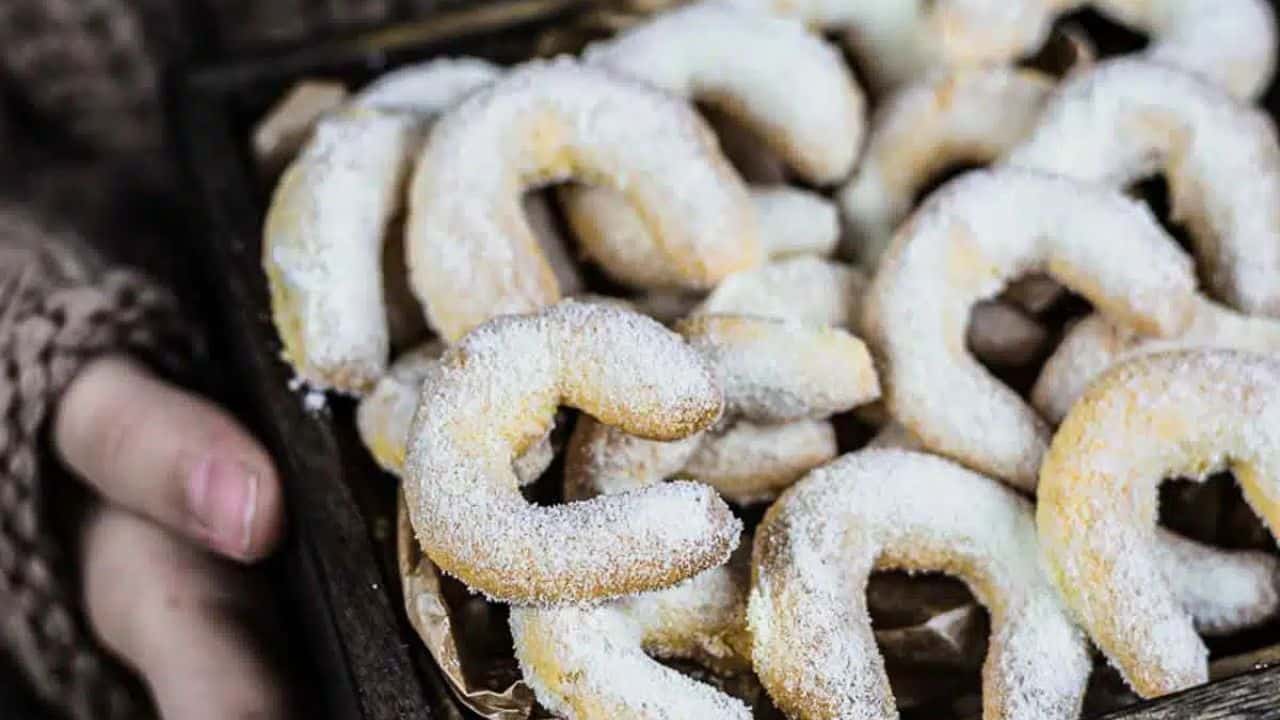 A tray of crescent-shaped cookies dusted with powdered sugar.