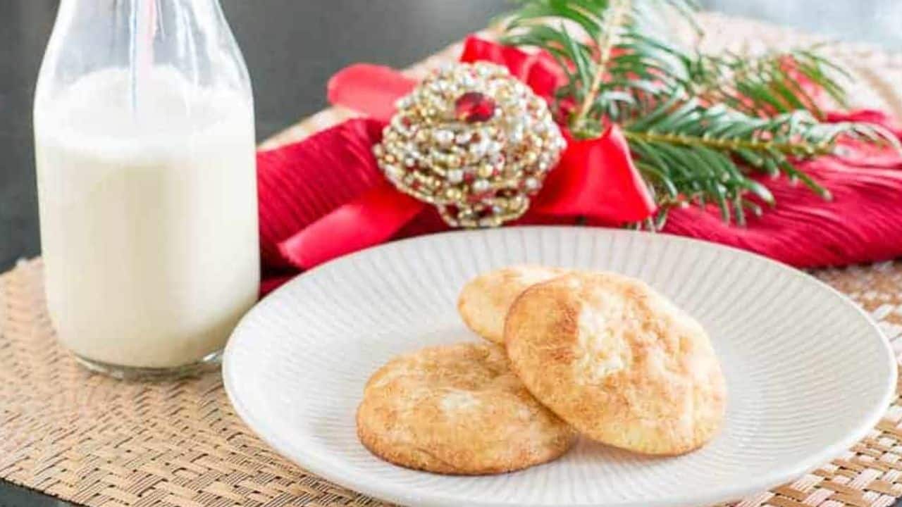 Overhead shot of a plate with three cookies next to a wire rack filled with cooling cookies.