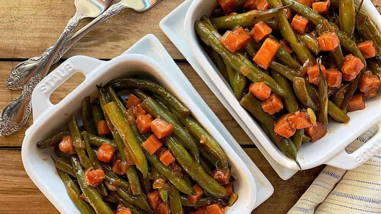 A white bowl with barbecued green beans and chuncks of ham.