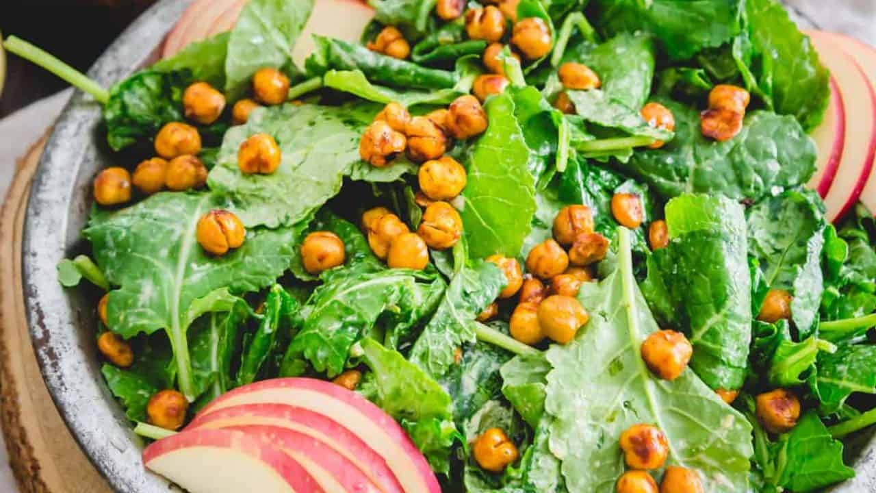 Baby kale salad in a metal plate with apples and roasted chickpeas.