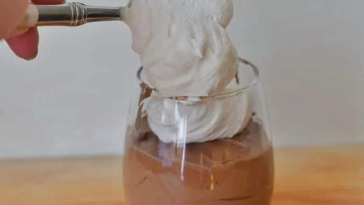 Image shows a Spoon with Baileys chocolate mousse and whipped cream and the full serving behind it.