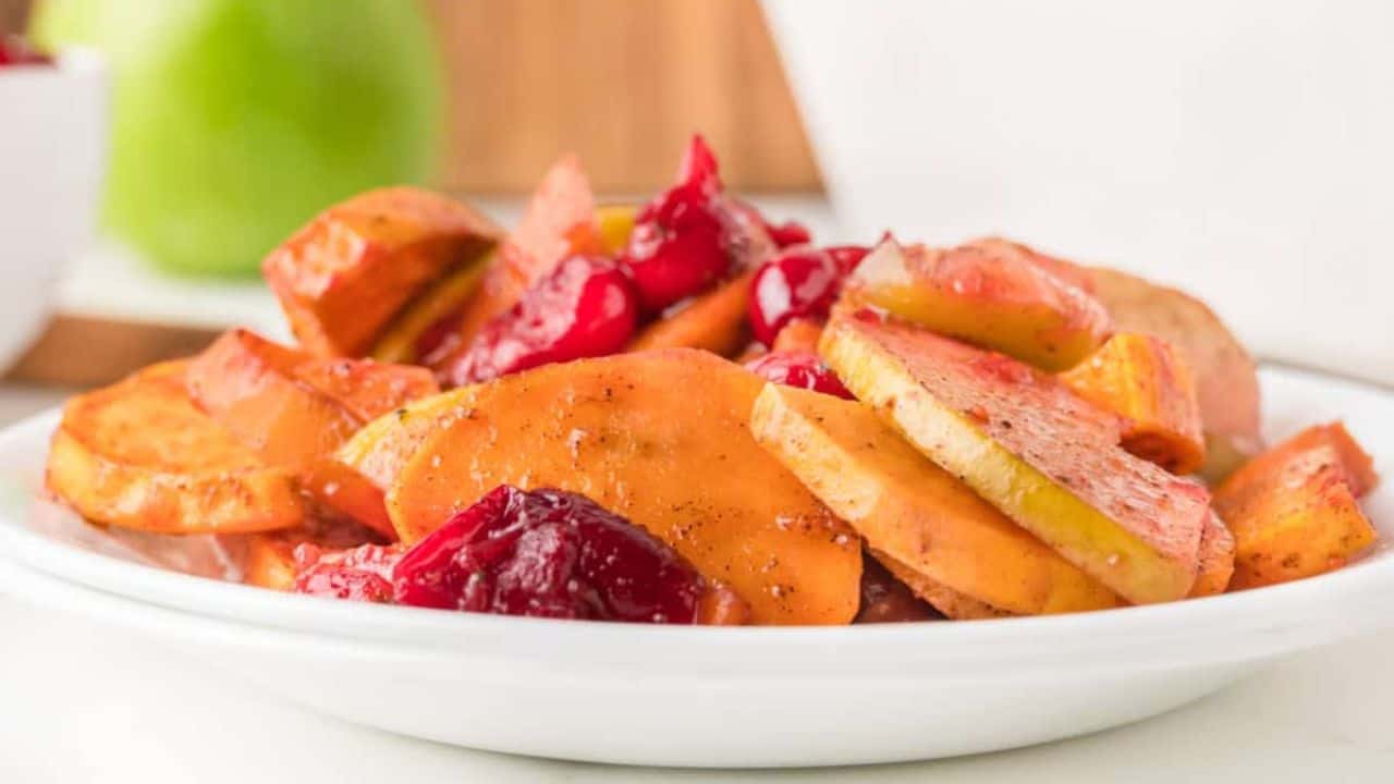 A spoonful of sweet potato slices with apples and cranberries in a white dish.
