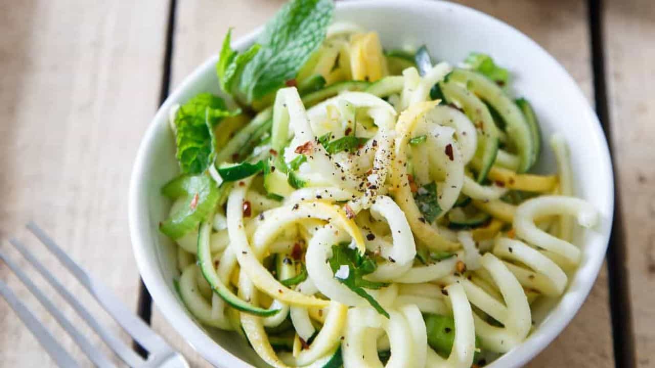 Basil mint squash noodles with freshly ground black pepper in a white bowl.