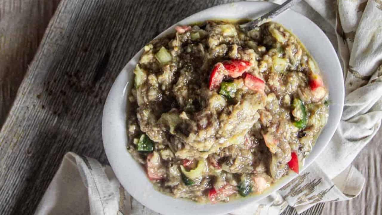 Zaalouk in a white plate with spoon and napkin.