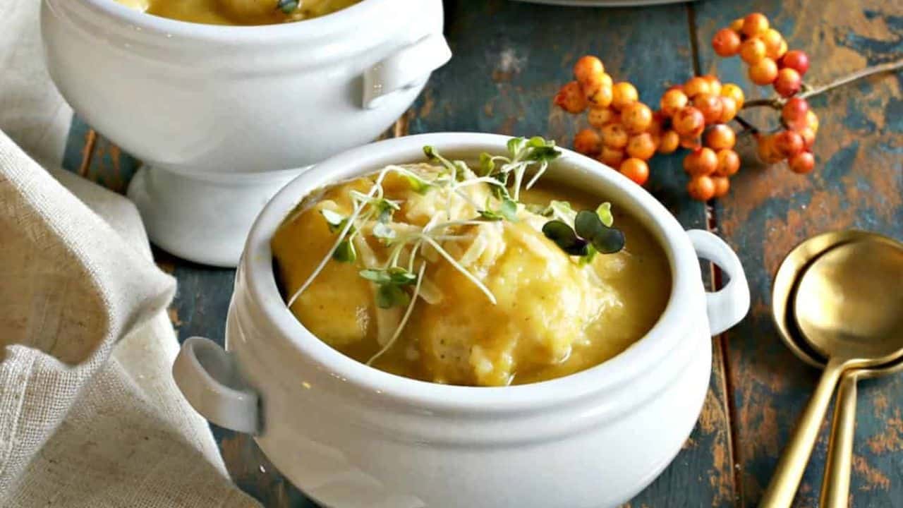 Two bowls of butternut squash soup on a wooden table.