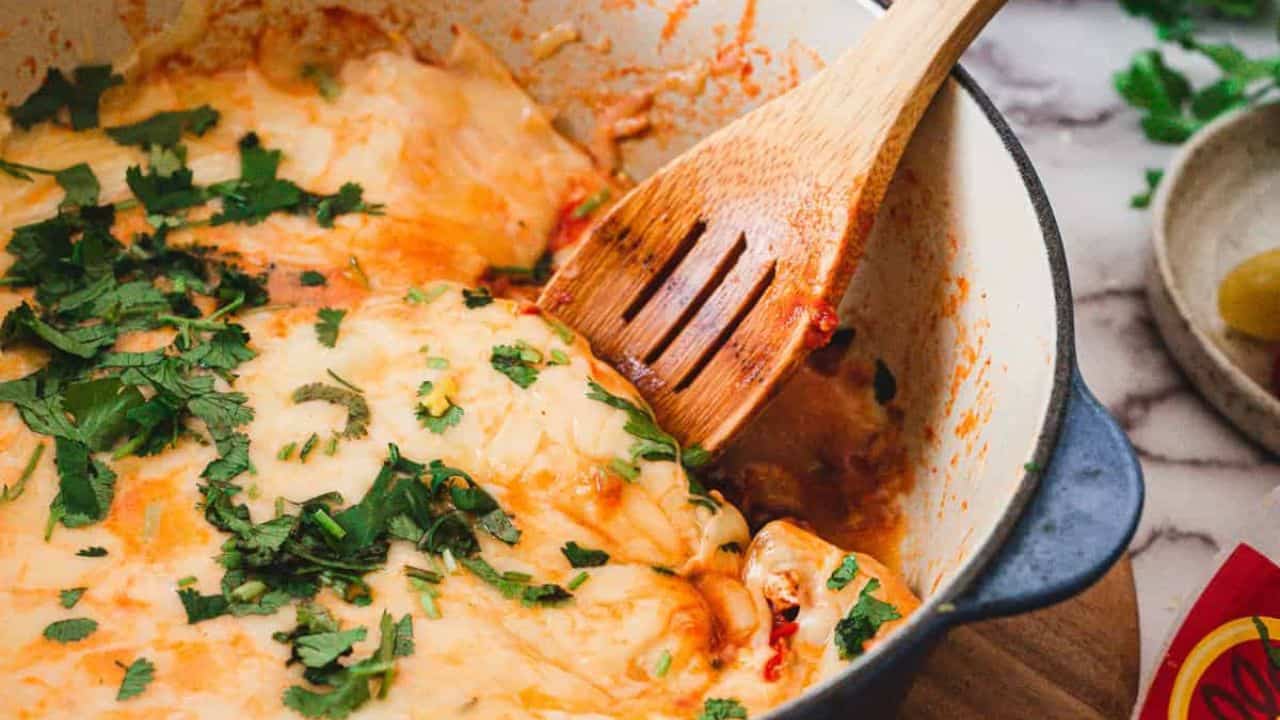 A person scooping a dish of eggs in a skillet.