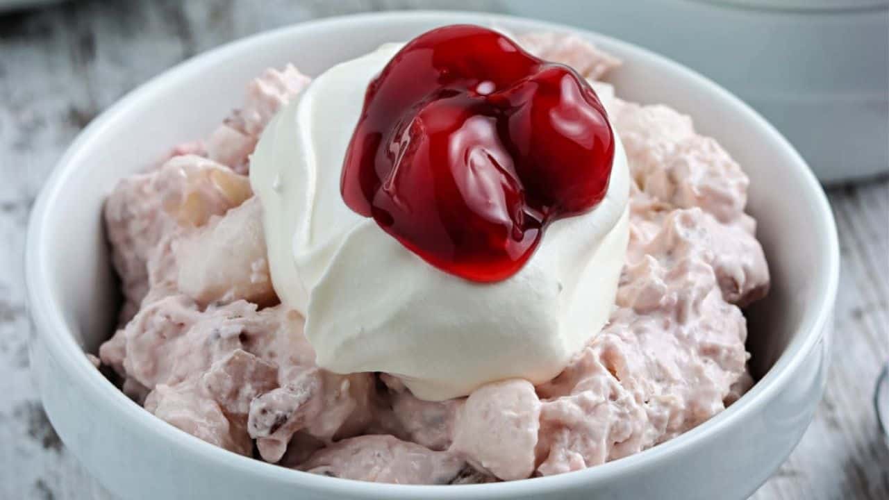 Cherry fluff salad in blue bowls with whipped cream.