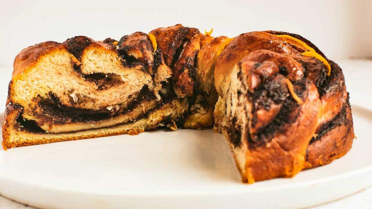 Low angle shot of a chocolate babka with a wedge removed so you can see the inside.