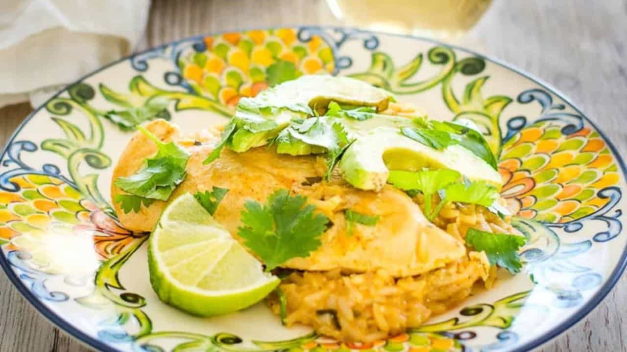Cilantro lime chicken on a plate next to avocado and cilantro garnish.