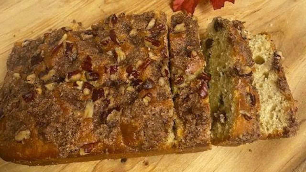 Loaf of cinnamon raisin bread with two slices falling forward on wooden board.