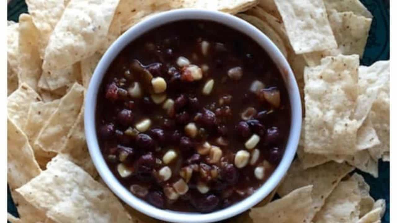 A bowl corn and black bean salsa with chips around.