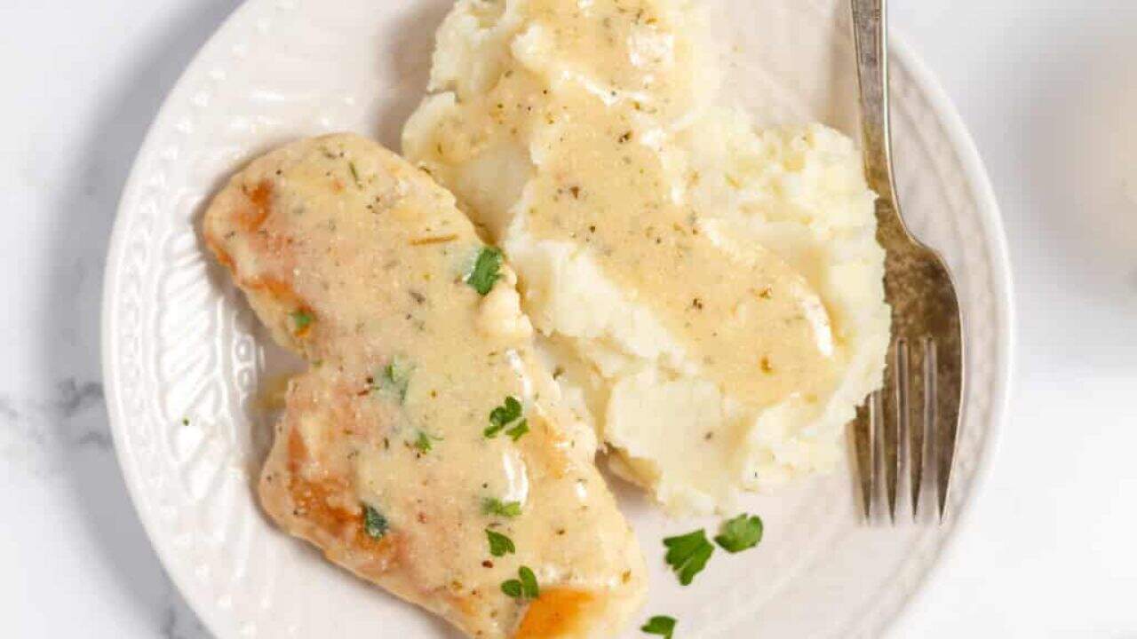 Chicken cutlets in cream sauce in a skillet.