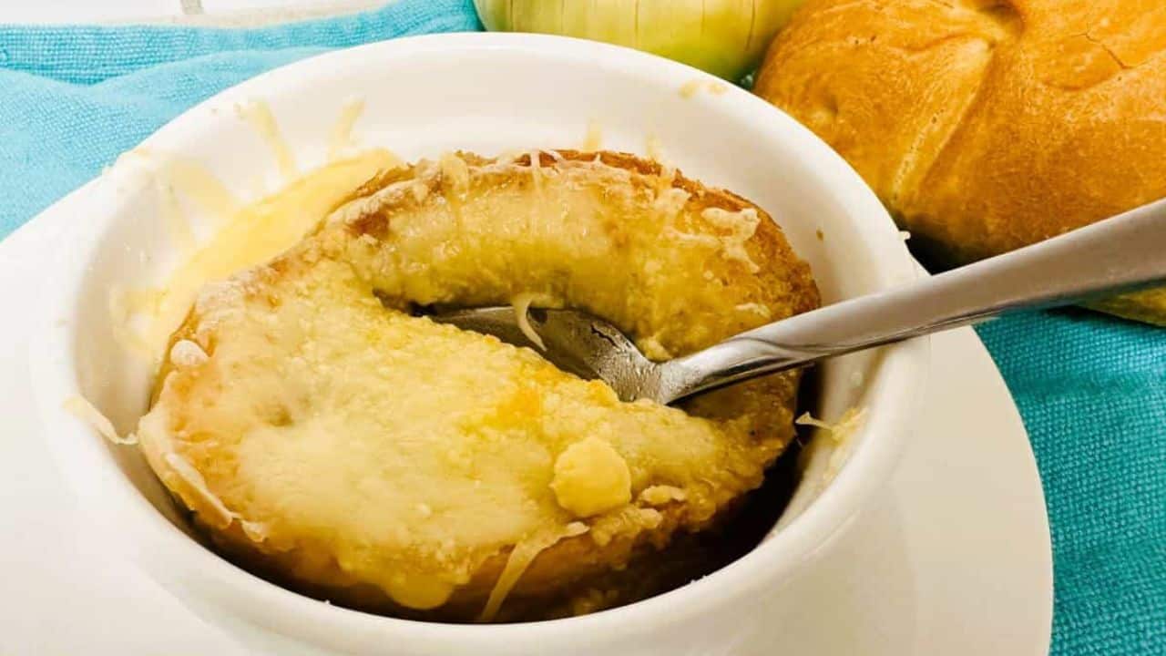 A bowl of French onion soup with a spoon next to it.