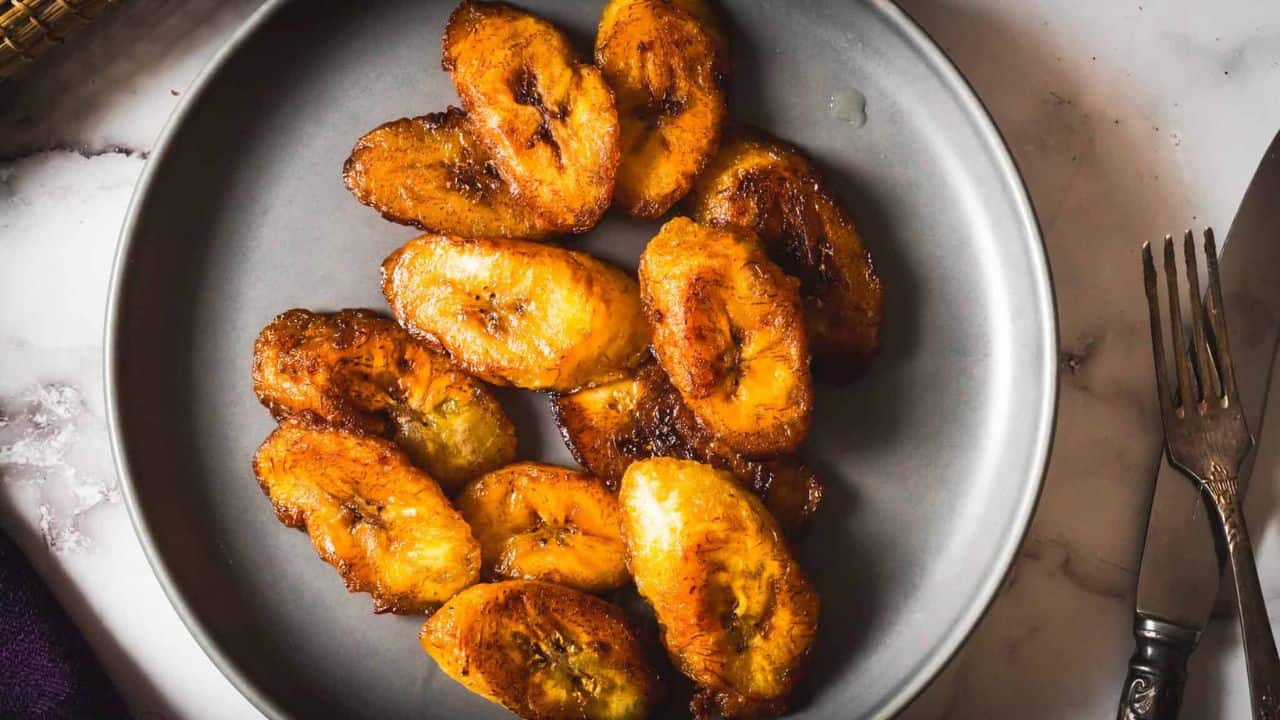 A plate of fried bananas on a marble table.