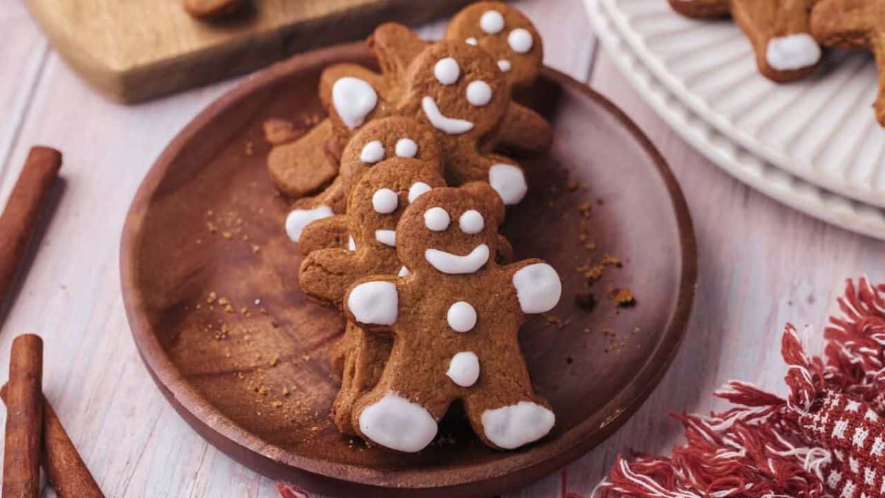 A line of gingerbread man cookies on a wooden plate.