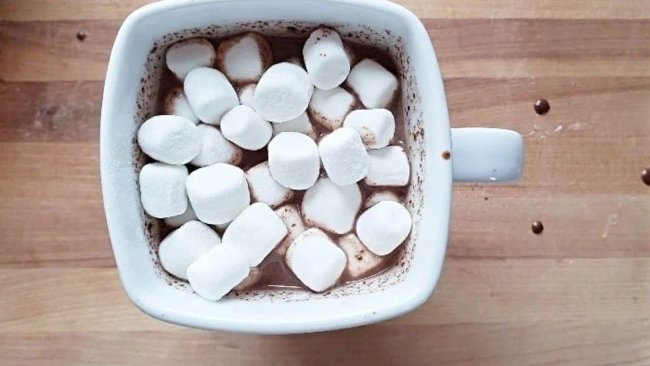 Image shows hot milk being poured into a mug with chocolat chaud base.