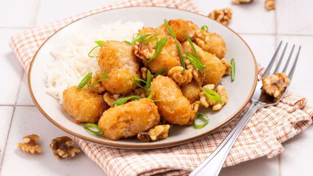 Close-up of plated honey walnut shrimp with a bowl of walnuts.