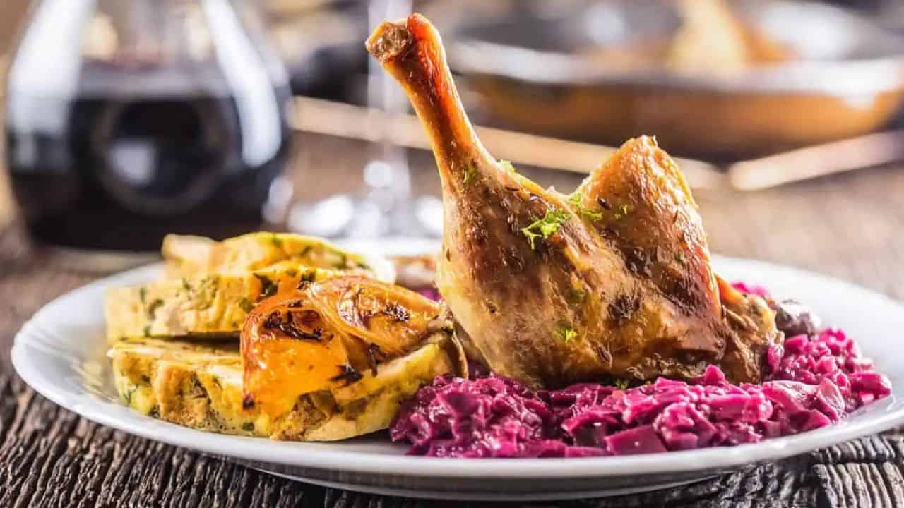 Overhead shot of a confit duck leg with orange sauce and star anise pods.