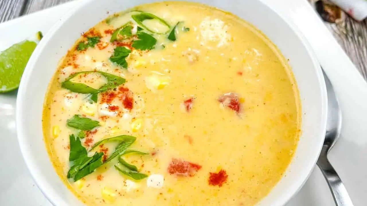 Mexican street style corn soup in a white bowl on a white plate.