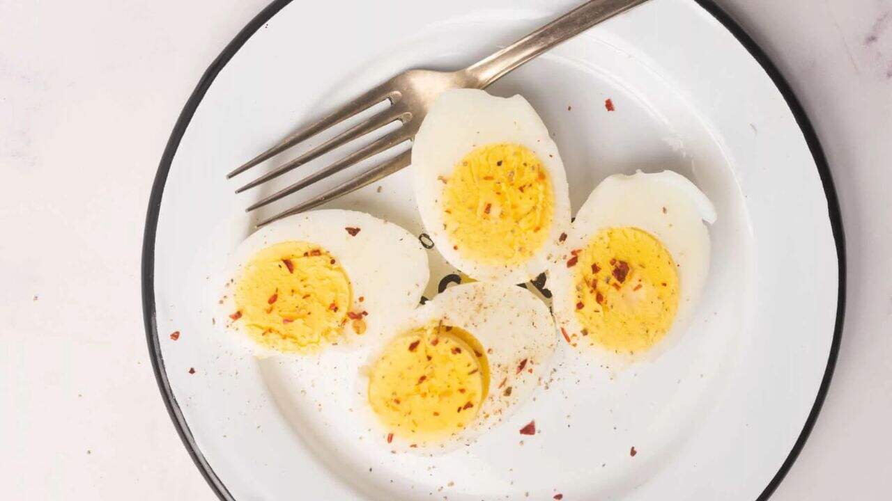 Overhead view of hard boiled eggs on a white plate.