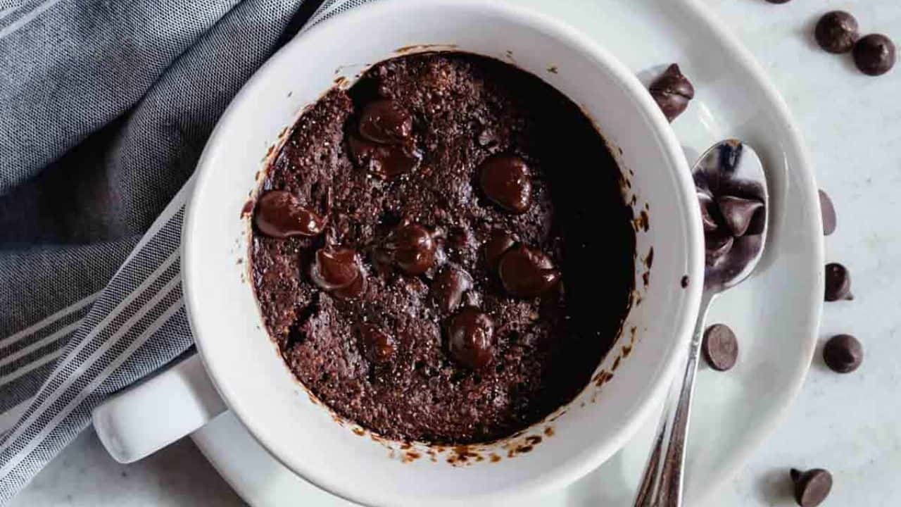 Chocolate protein mug cake in a white bowl with a spoon.