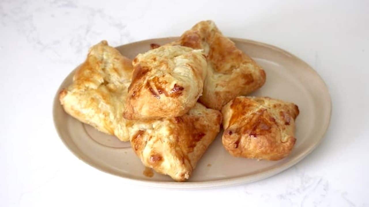 A plate with puff pastry cheese pockets on it.