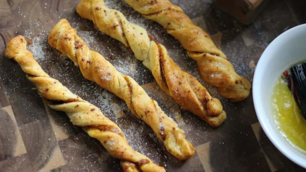 Pumpkin spice churros on a wooden serving board with a bowl of butter off to the right side.