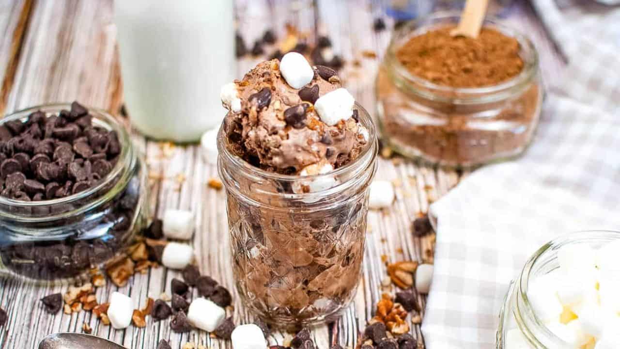 A jar of Rocky Road Ice Cream on a table with ingredients scattered around.
