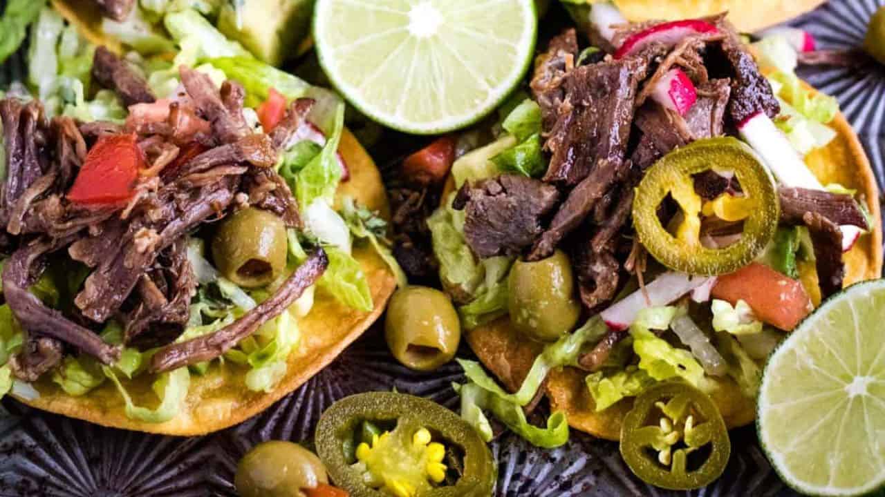 Low angle shot of mini tostadas with salpicon de res or shredded beef salad on top.