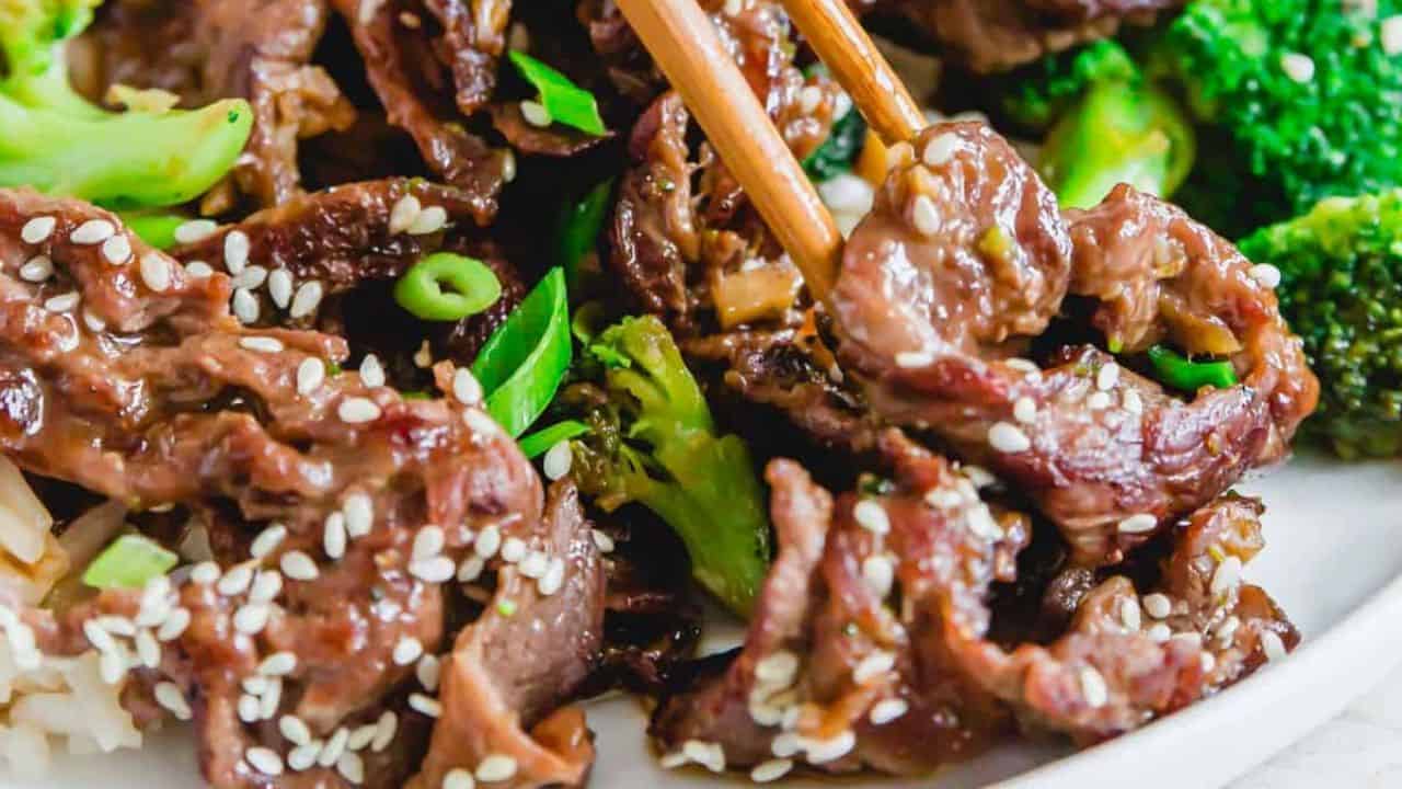 Beef and broccoli stir fry served with white rice on a white plate.