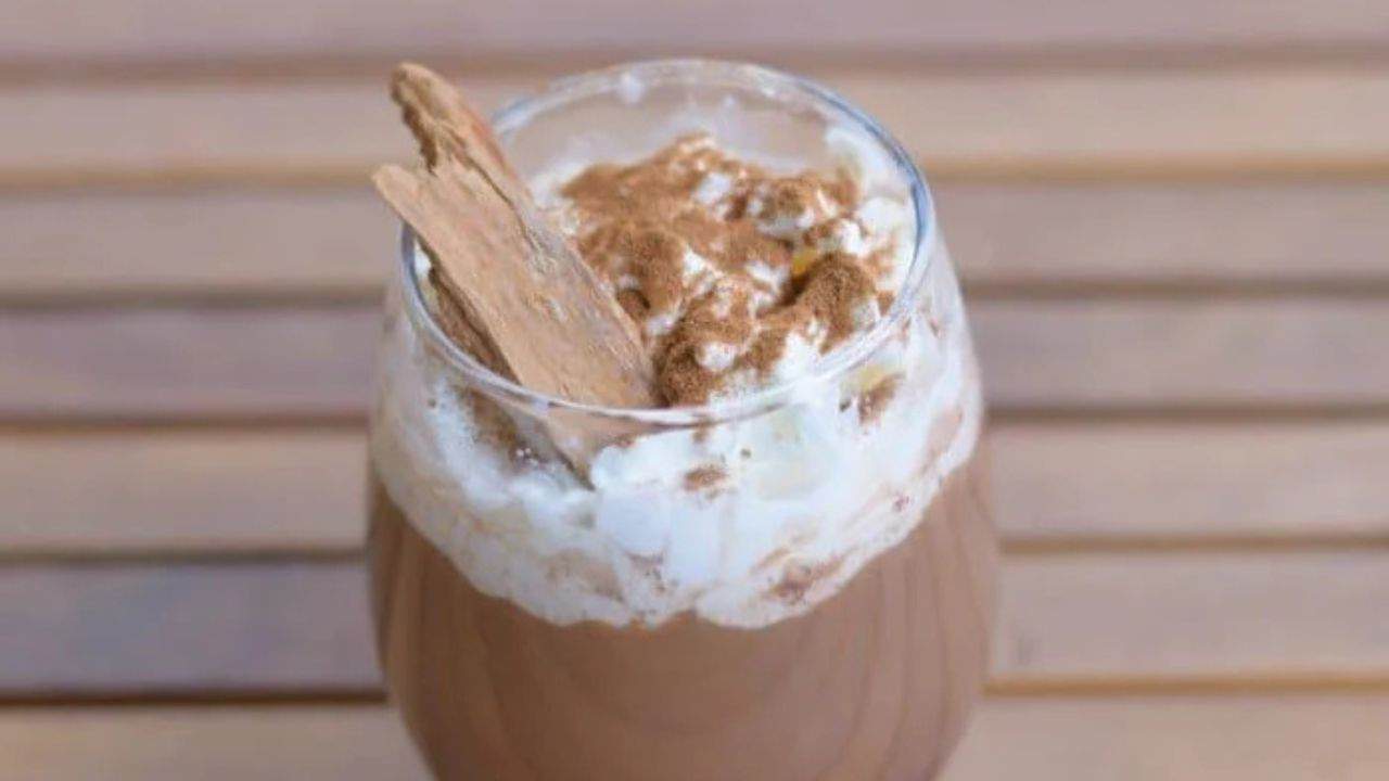 Image shows a Spicy Cinnamon Mocha in a clear glass with a cinnamon stick in the foam.