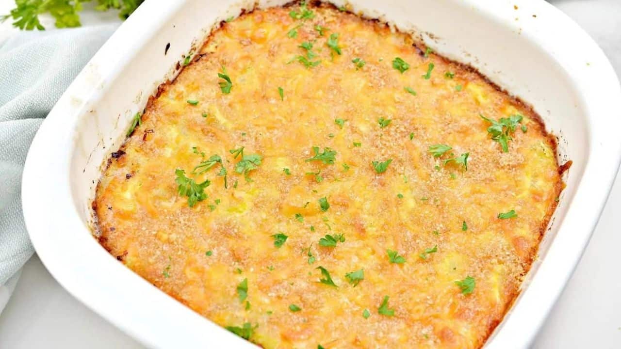 Cheesy squash casserole in a white dish.