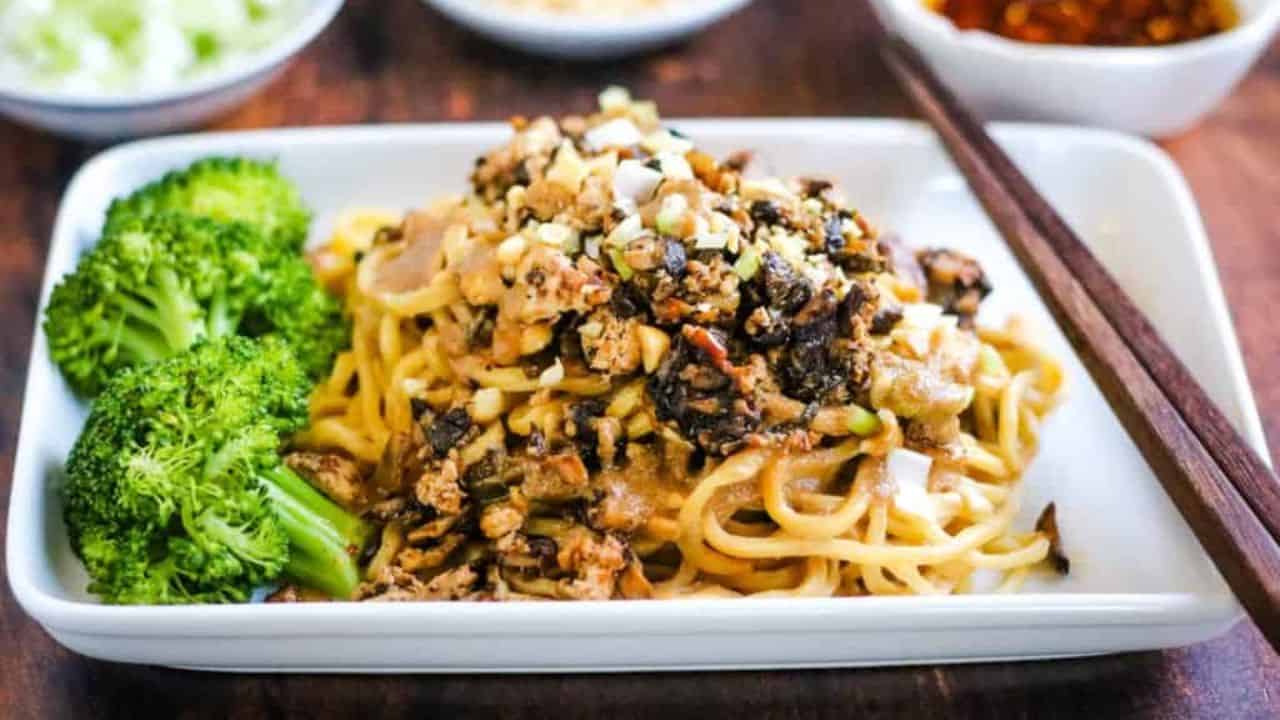Low angle shot of a plate of vegetarian dan dan noodles with broccoli.