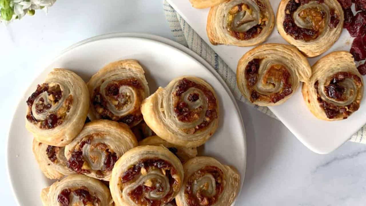 Pear and cranberry pinwheels on a white board.